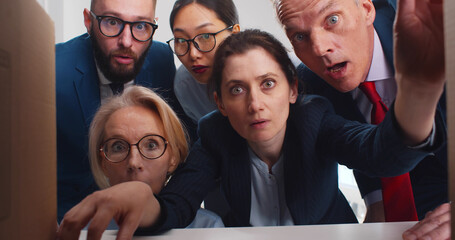 Team of surprised business people looking inside paper box