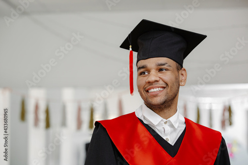Portrait of a smiling Black student, wearing a graduation gown and a square cap with a red tassel of the class of 2021