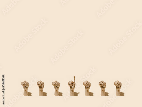 From above of pattern of wooden hands with clenched fists and one with index finger pointing up on beige background
