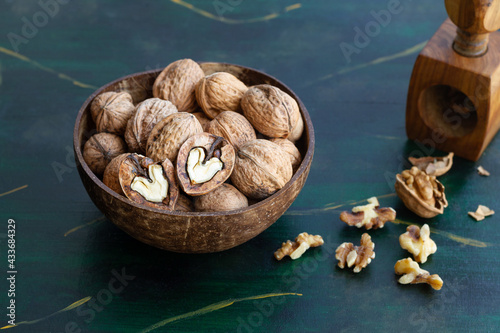 Round shaped wooden bowl full of crunchy walnuts with dry uneven nutshells on table photo