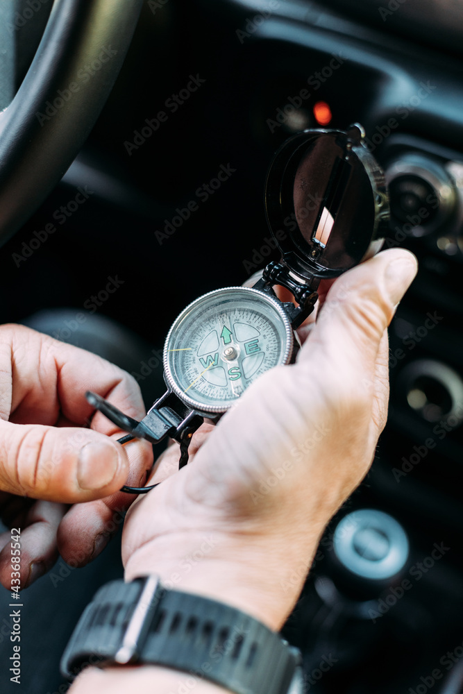 Anonymous adventurer holding a compass to orient himself inside his car Anonymous adventurer holding a compass to orient himself inside his car