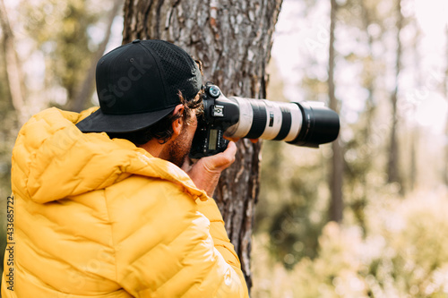 Side view of an adventurous photographer taking photos in the mountain with blur background photo