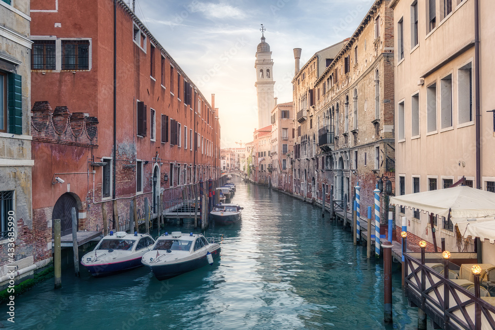 Boats moored on water canal between shabby residential buildings under sunset sky in Venice Boats moored on water canal between shabby residential buildings under sunset sky in Venice