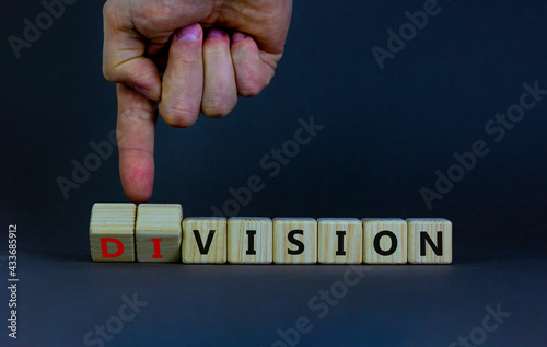 Division or vision symbol. Businessman turns wooden cubes and changes the word 'division' to 'vision'. Beautiful grey table, grey background. Business, division or vision concept. Copy space.