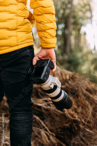 Rear view of an anonymous photographer holding his camera in the mountain with blur background photo