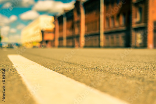 Summer in the city, the empty street with the building of red brick. Close up view from the level of the dividing line © Georgii Shipin
