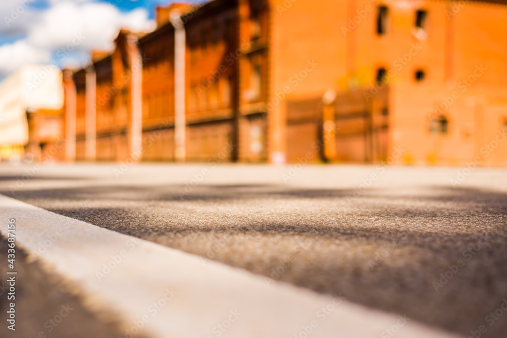 Fototapeta premium Summer in the city, the empty street with the building of red brick. Close up view from the level of the dividing line