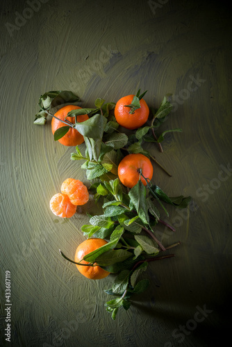 From above mandarin with pedicel and foliage on surface near peppermint laves