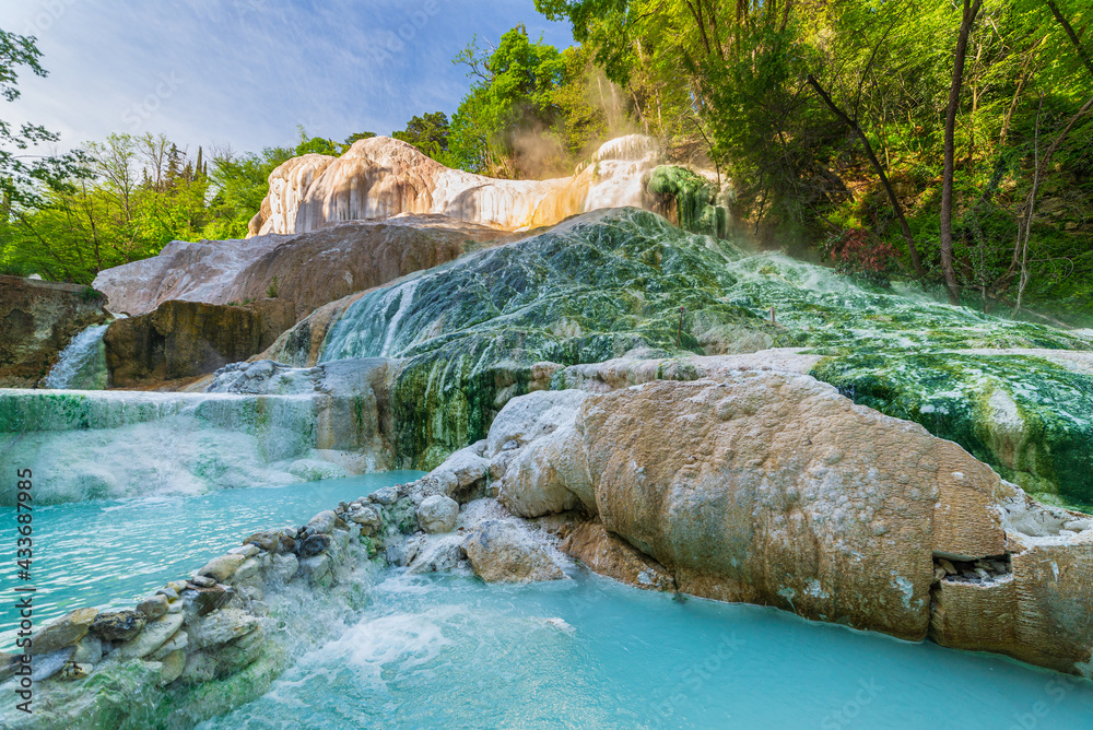 Naklejka premium Geothermal pool and hot spring in Tuscany, Italy. Bagni San Filippo natural thermal waterfall in the morning with no people. The White Whale amidst forest.