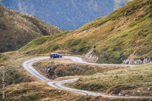 Modern automobile driving on dusty path in green mountains of Pyrenees with forest in Spain photo