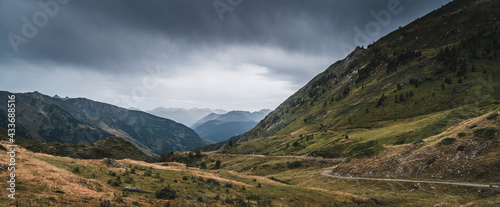 Landscape of Aran valley with majestic green hills and dark gray gloomy sky above photo