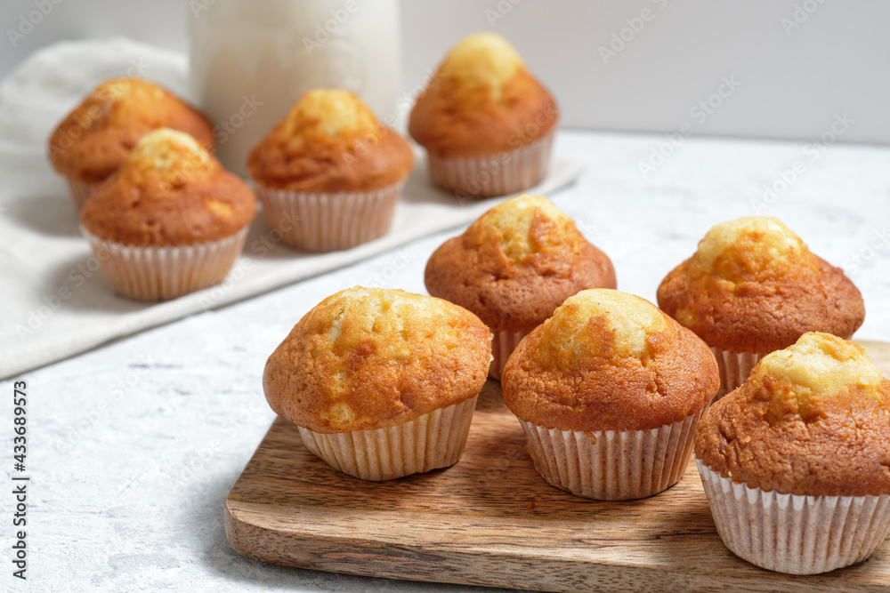Yummy homemade freshly baked sweet muffins in paper cups arranged on table with glass jar of fresh milk Yummy homemade freshly baked sweet muffins in paper cups arranged on table with glass jar of fresh milk