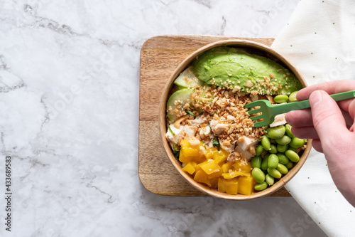 From above of anonymous crop person eating delicious homemade poke served on wooden board on table