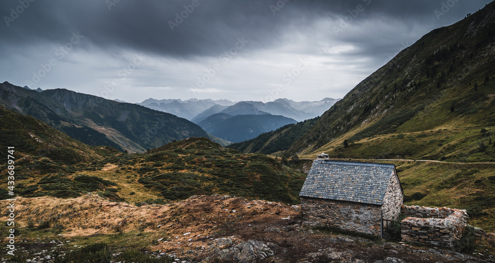 Wide angle of small brick building on grassy field in marvellous Pyrenees mountains under overcast sky in Catalonia Wide angle of small brick building on grassy field in marvellous Pyrenees mountains under overcast sky in Catalonia