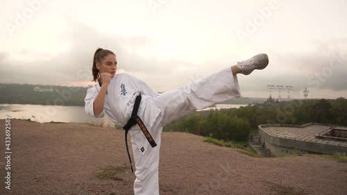 Translation: Kyokushinkai. young beautiful girl karate does handstand on one leg on nature on background river ,forest photo