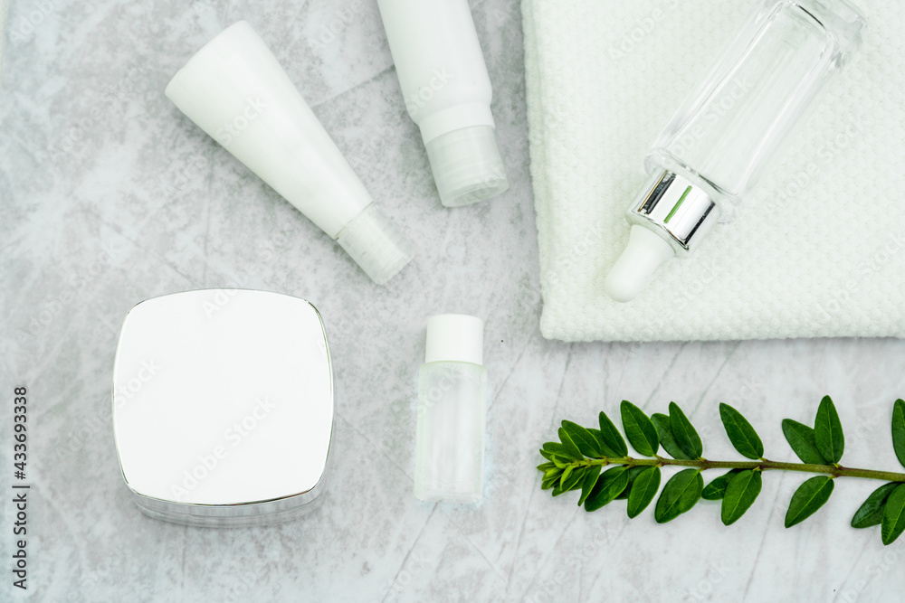 cosmetically flat lay: jars of skin care cosmetics in silver colour, white towel and a sprig of luscious greenery cosmetically flat lay: jars of skin care cosmetics in silver colour, white towel and a sprig of luscious greenery