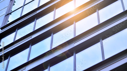 Modern architecture with sun ray. Glass and steel facade on a bright sunny day with sunbeams on the blue sky. Economy, finances, business activity concept.