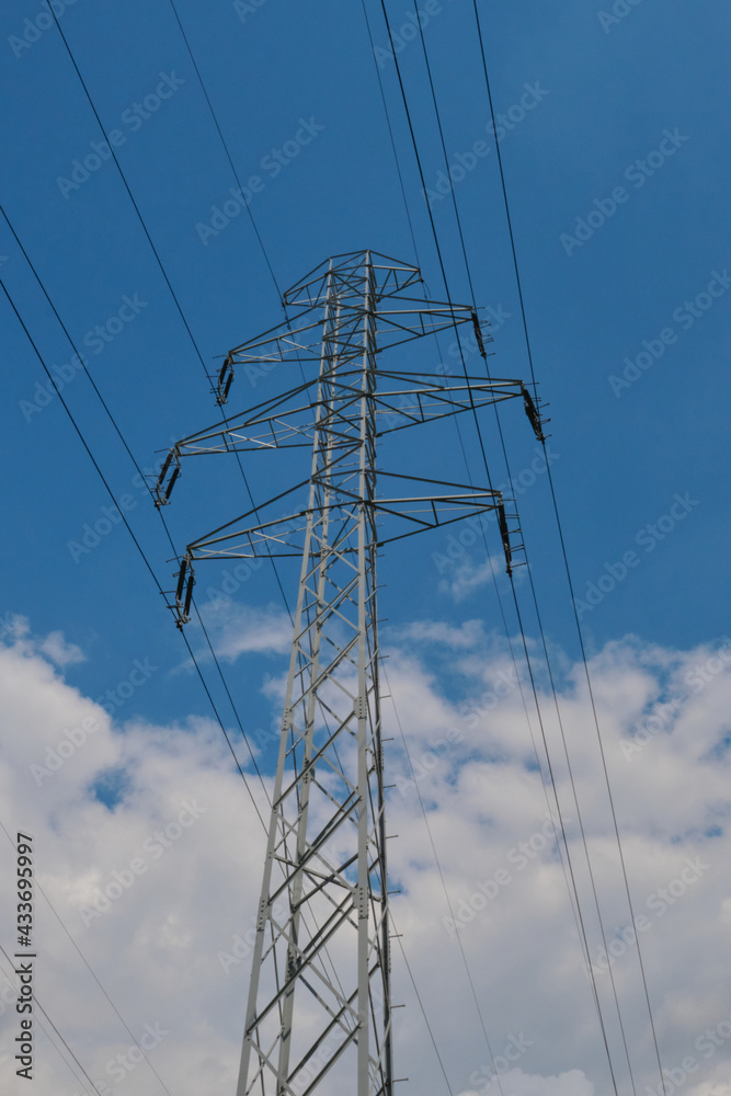 Electricity transmission pylon silhouette blue sky light cloudy noon hours