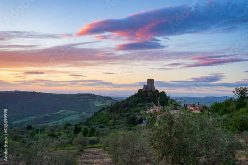 Rocca d Oria  a medieval village and fortress in Orcia Valley  Tuscany  Italy. Unique view at dusk  the stone tower perched on rock cliff against dramatic sky.