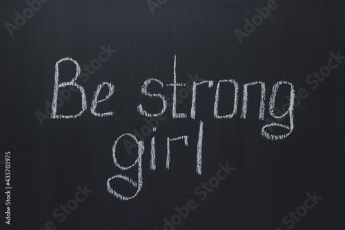 Lettering on a dark chalk school board Be strong girl. Motivational lettering