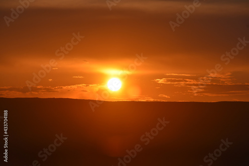 view of the red sun at sunset over the mountain