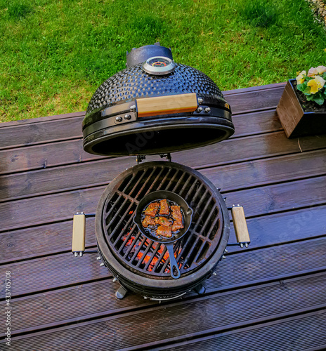 Foto A kamado egg type barbeque grill with a pan with a pan with roast beef standing on a living house terrace