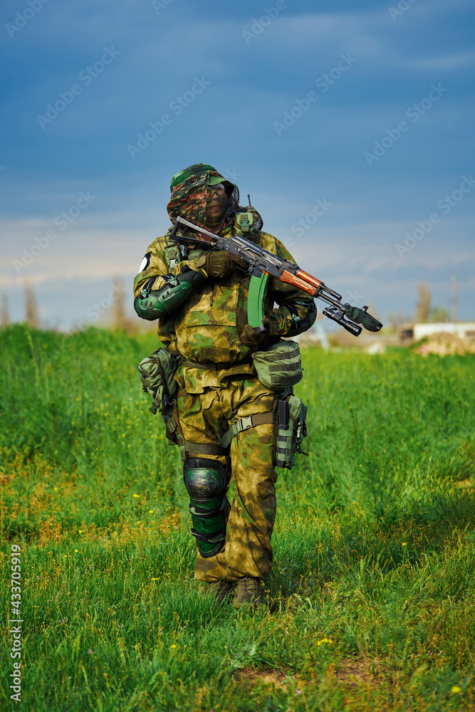 Airsoft player in the uniform of a Russian soldier holding a weapon in his hands