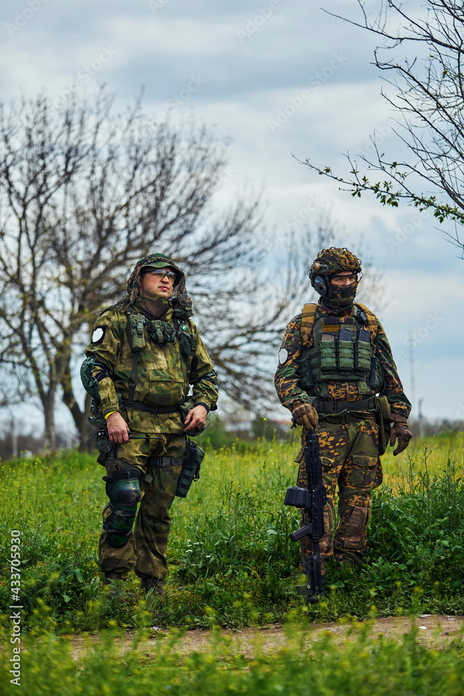 Two soldiers in outfit with weapons in the field Two soldiers in outfit with weapons in the field