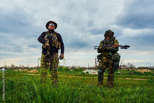 Two soldiers with weapons in their hands stand in the field