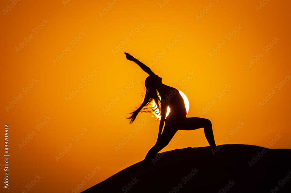 Silhouette of a young woman doing yoga pose at sunset Silhouette of a young woman doing yoga pose at sunset