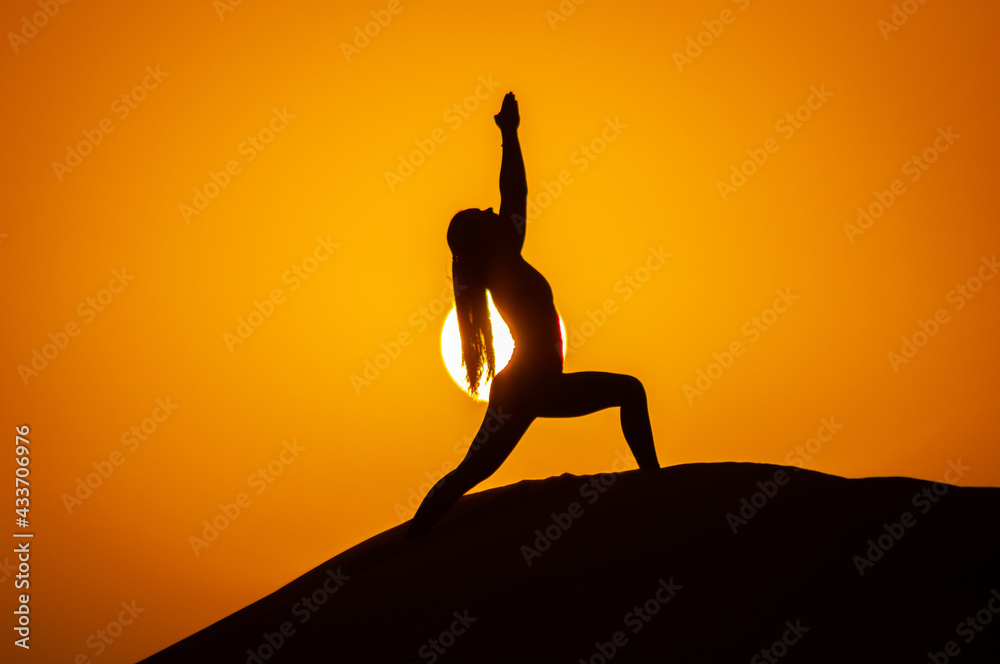 Silhouette of a young woman doing yoga pose at sunset Silhouette of a young woman doing yoga pose at sunset
