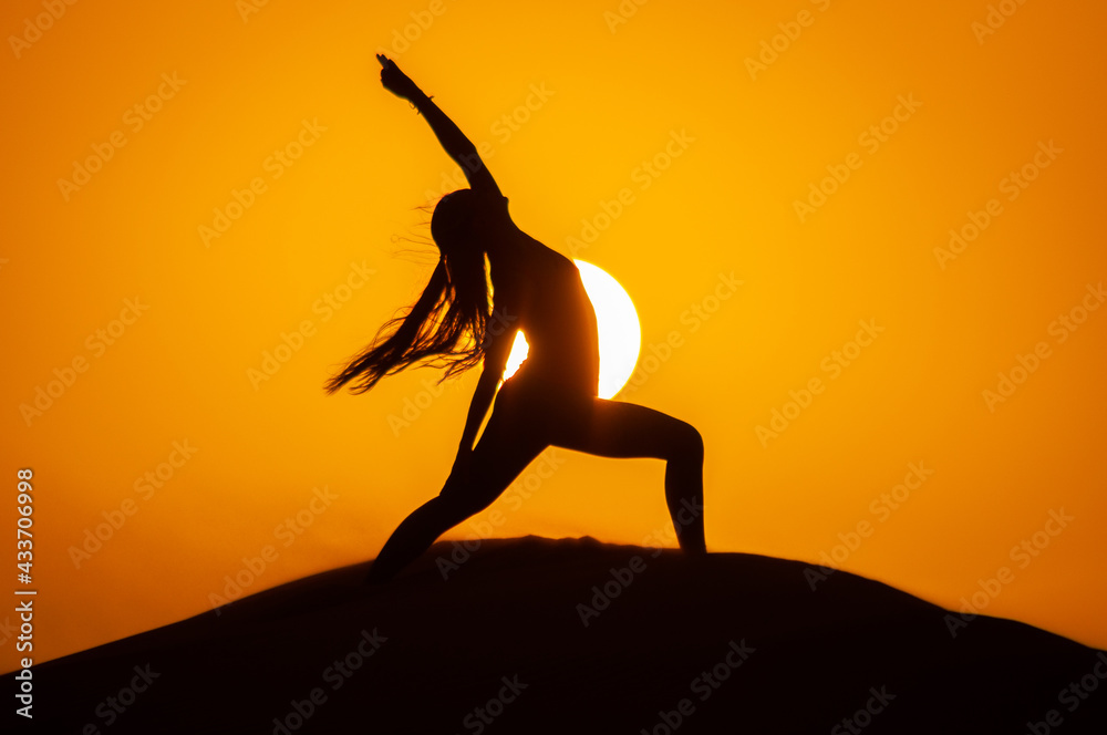 Silhouette of a young woman doing yoga pose at sunset Silhouette of a young woman doing yoga pose at sunset