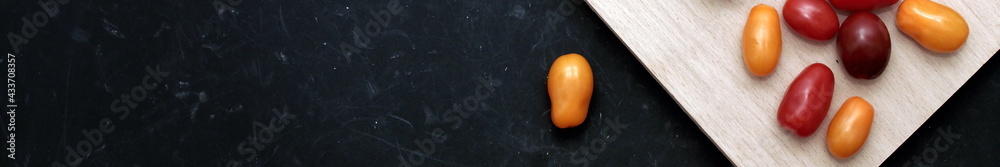 Plum Cherry Tomatoes On White Cutting Board. Assorted Plum Cherry Tomatoes On Wooden Cutting Board. Scattered Red, Yellow And Black Plum Cherry Tomato On Black Shabby Background. Plum Cherry Tomatoes On White Cutting Board. Assorted Plum Cherry Tomatoes On Wooden Cutting Board. Scattered Red, Yellow And Black Plum Cherry Tomato On Black Shabby Background.