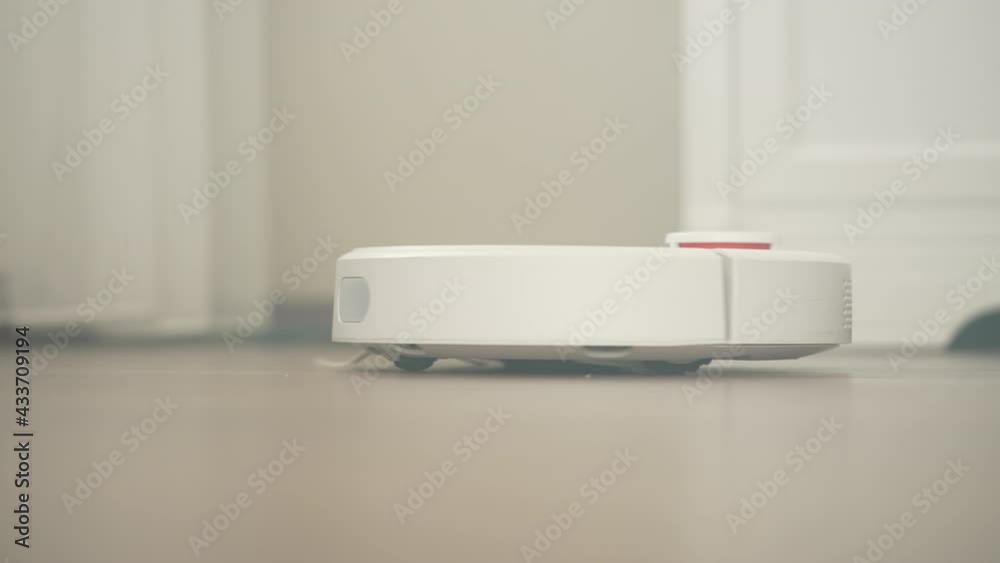 Cleaning the house with the latest technology. The robot vacuum cleaner rolls on the floor and vacuumes the dust. Cleaning the living room in the house. Cleaning the house with the latest technology. The robot vacuum cleaner rolls on the floor and vacuumes the dust. Cleaning the living room in the house.