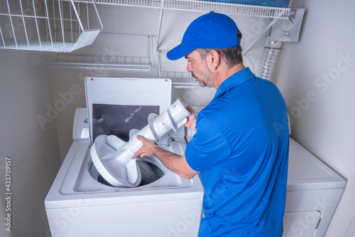 Appliance technician in uniform servicing a washing machine