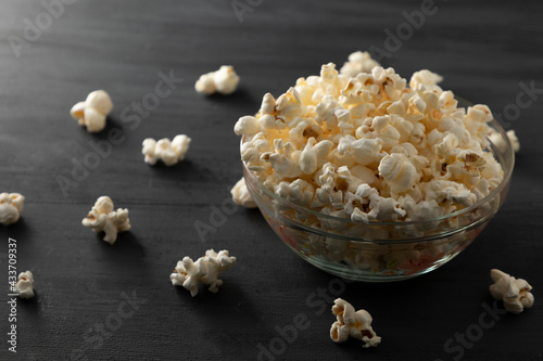 Palomitas de maíz en un recipiente con palomitas tiradas en la mesa de color negro photo