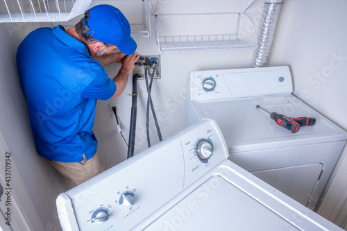 Fototapeta Plumber installing a residential washing machine