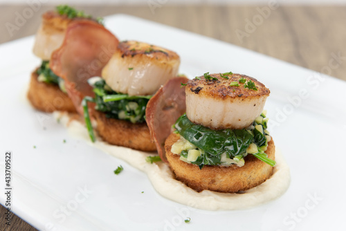 Seared Scallops sitting atop a bed of spinach served as a threesome for your seafood appetite