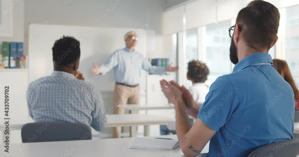 Excited multiethnic students smiling and applauding to mature professor Excited multiethnic students smiling and applauding to mature professor