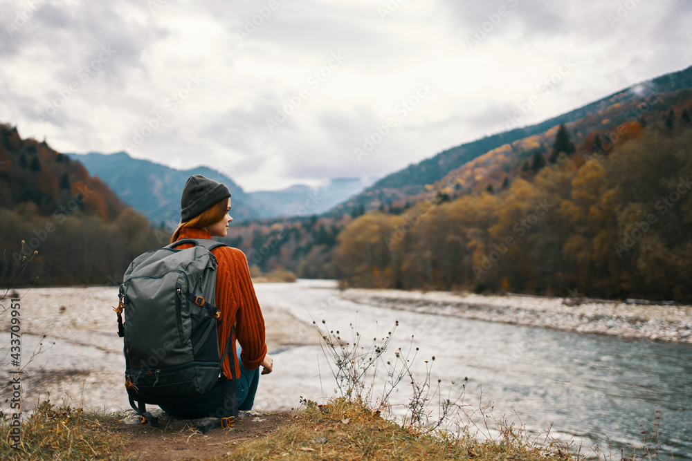 a traveler in a jacket with a backpack on her back hat mountains landscape river a traveler in a jacket with a backpack on her back hat mountains landscape river