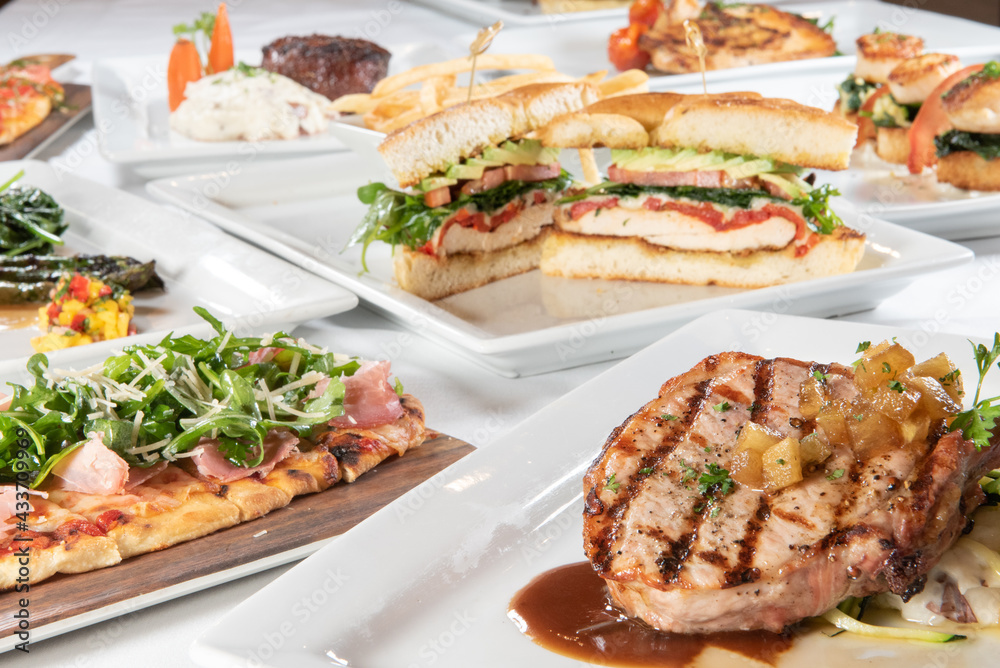 Huge selection of different restaurant plates of food with a delicious pork chop up in front Huge selection of different restaurant plates of food with a delicious pork chop up in front
