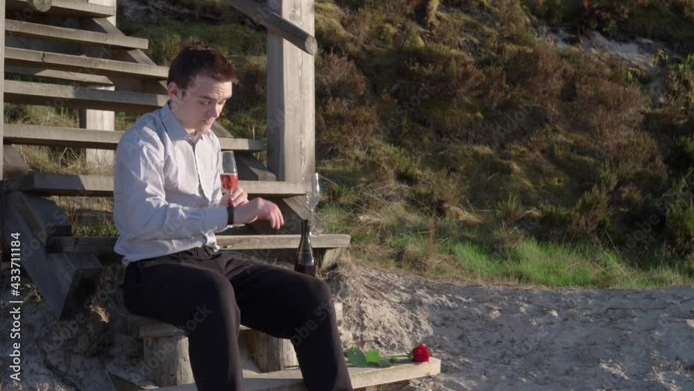 A guy is waiting for a girl on a date, he is tired of waiting, he drinks champagne, he is wearing a shirt and sweatpants, the concept of a meeting and a date, waiting A guy is waiting for a girl on a date, he is tired of waiting, he drinks champagne, he is wearing a shirt and sweatpants, the concept of a meeting and a date, waiting