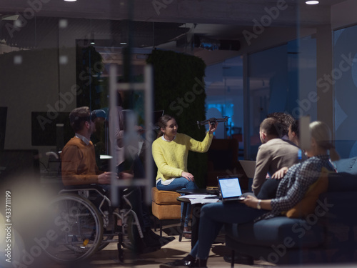 Disabled businessman in a wheelchair at work in modern open space coworking office with team using virtual reality googles drone assistance simulation