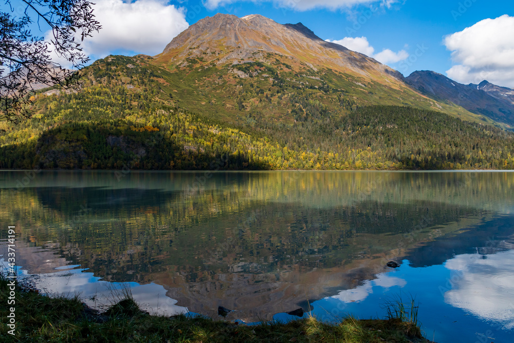 mountain and autumn foliage of trees reflection on a calm lake in the Kenai peninsula in Alaska.