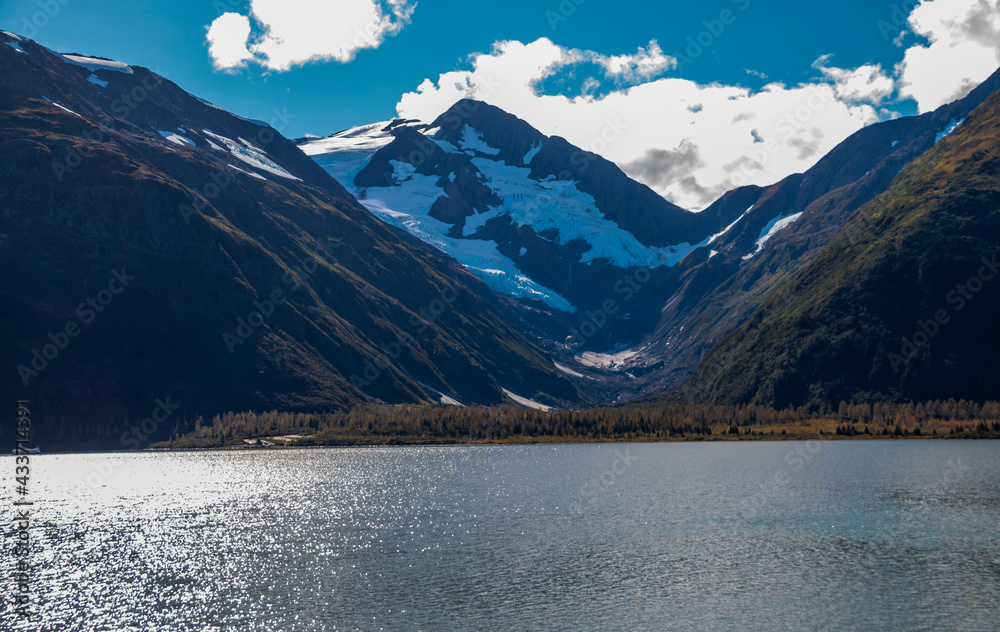 calm Portage lake under a clear blue sky against the glacier filled mountains of Alaska.
