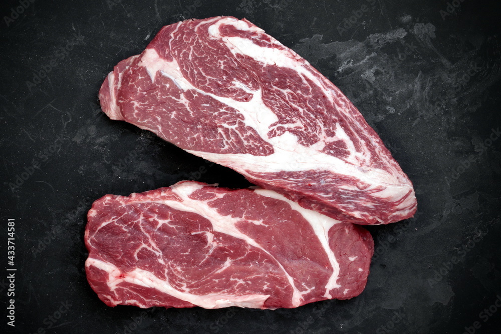 Raw Steaks. Sirloin Beef Steaks, Overhead View. Many Raw Striploin Steaks from Marbled Beef on Black Background. Group of Black Angus Beefsteaks. Raw Sirloin Cuts. Uncooked Prime Beef Steaks.