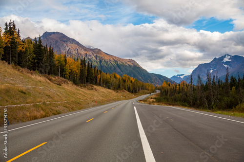 autumn road trip to the open roads of Alaska along the snow capped mountains and vibrant golden yellow foliage of autumn.