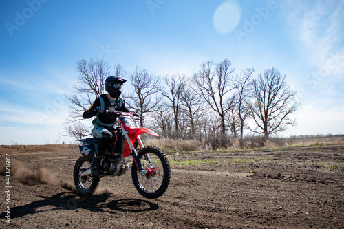 Fototapeta Naklejka Na Ścianę i Meble -  Dirt biker does a small wheeling coming out of a corner on a motocross track.