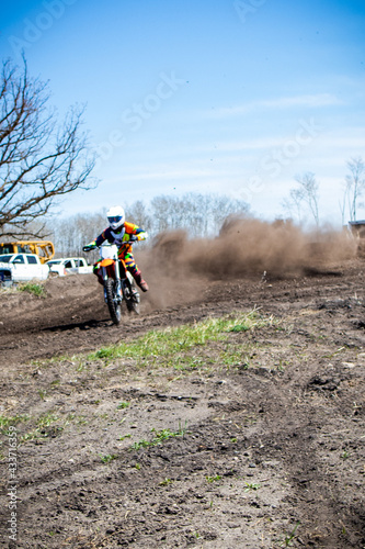 Motocross rider shoots dirt and dust coming out of a corner.