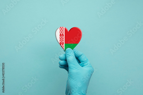 Hands wearing protective surgical gloves holding Belarus flag heart